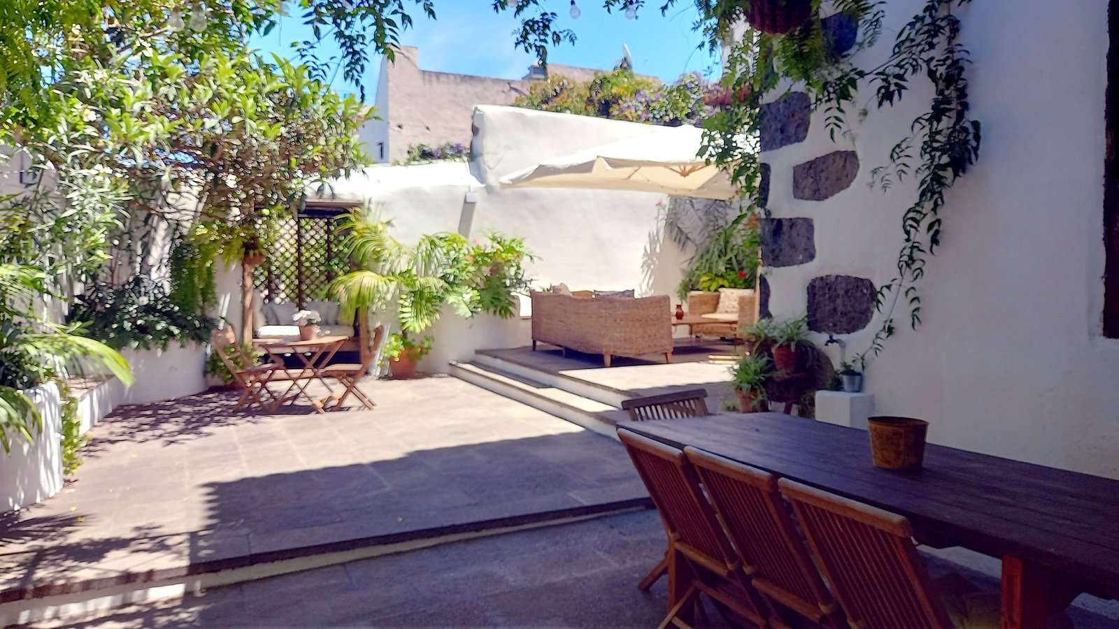 Patio interior con mesa y sillas de madera en Casa La Aldaba