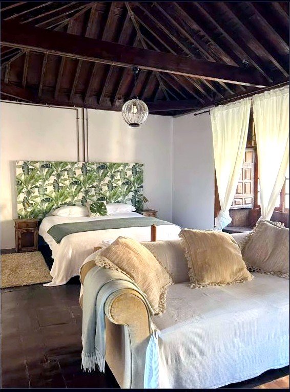 Dormitorio con techo de madera y zona de estar en Casa La Aldaba